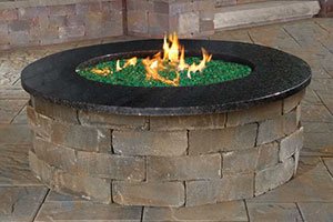 Custom stone fire pit with surrounding patio hardscaping built by Elegant Landscaping