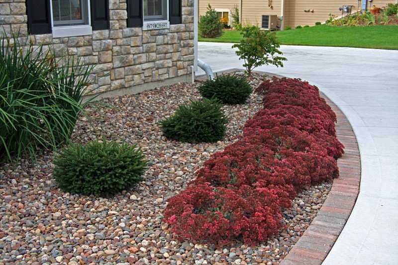 Decorative rock garden with red sedum plants and brick border by Elegant Landscaping in Erie PA