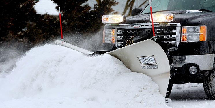 Commercial snow plow clearing a parking lot during an Erie PA winter storm